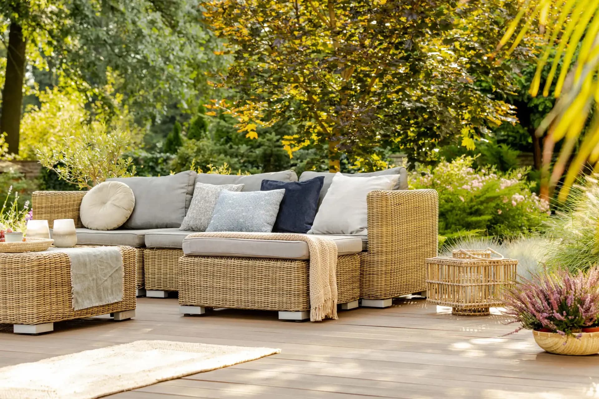 A light brown deck with light-colored wicker furniture with gray cushions.