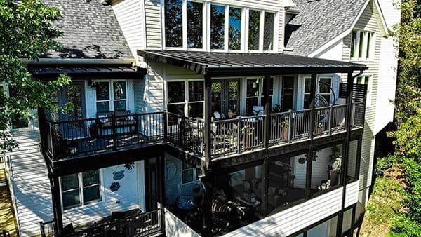 A two-story covered porch and deck off a white house.