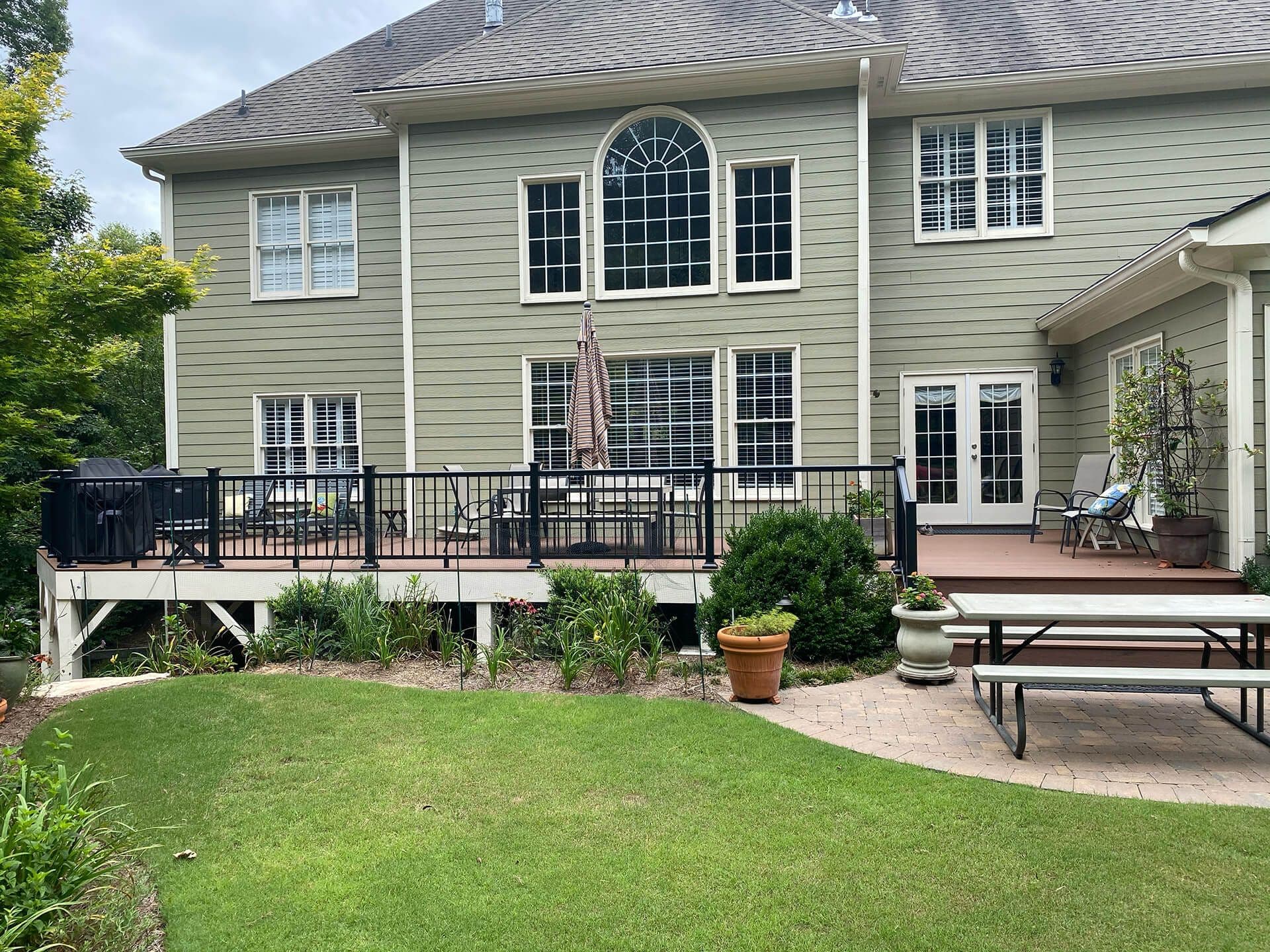 A large gray house with an elegant TimberTech deck that has a black railing.