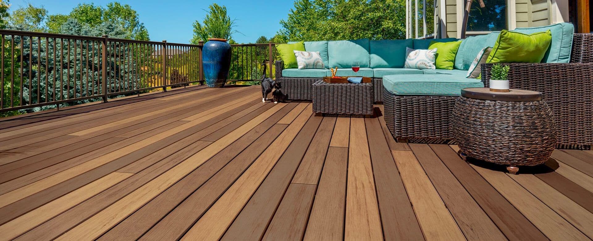 A brown TimberTech deck with dark brown and teal patio furniture.