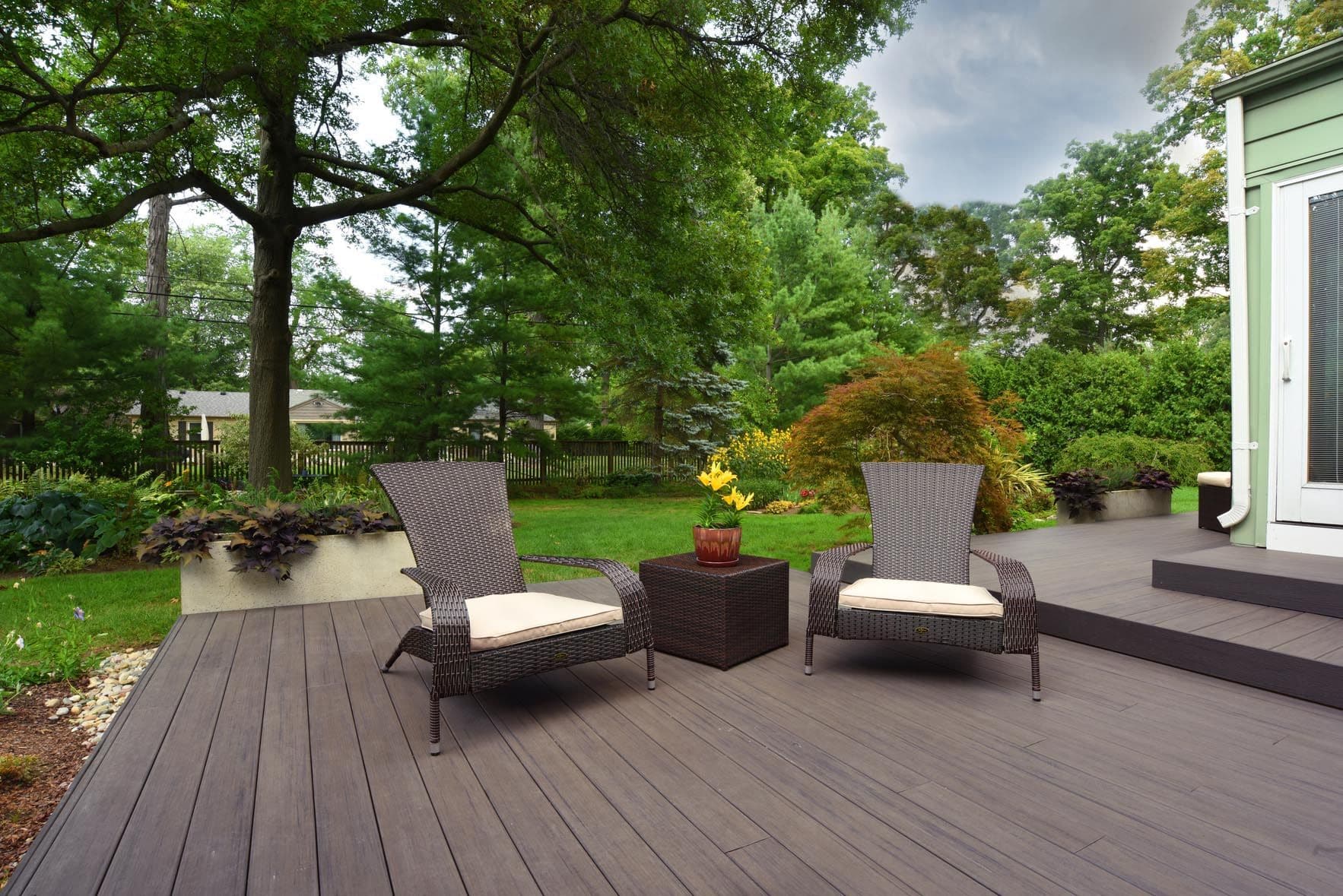 A TimberTech deck in a dark brown espresso color with two patio furniture chairs.