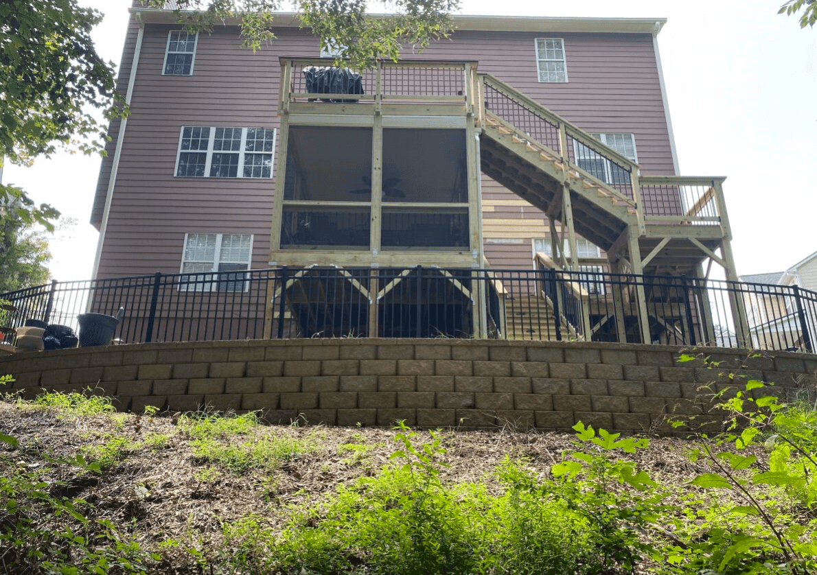 An upward-looking view of a brown house with a new two-story wood deck.