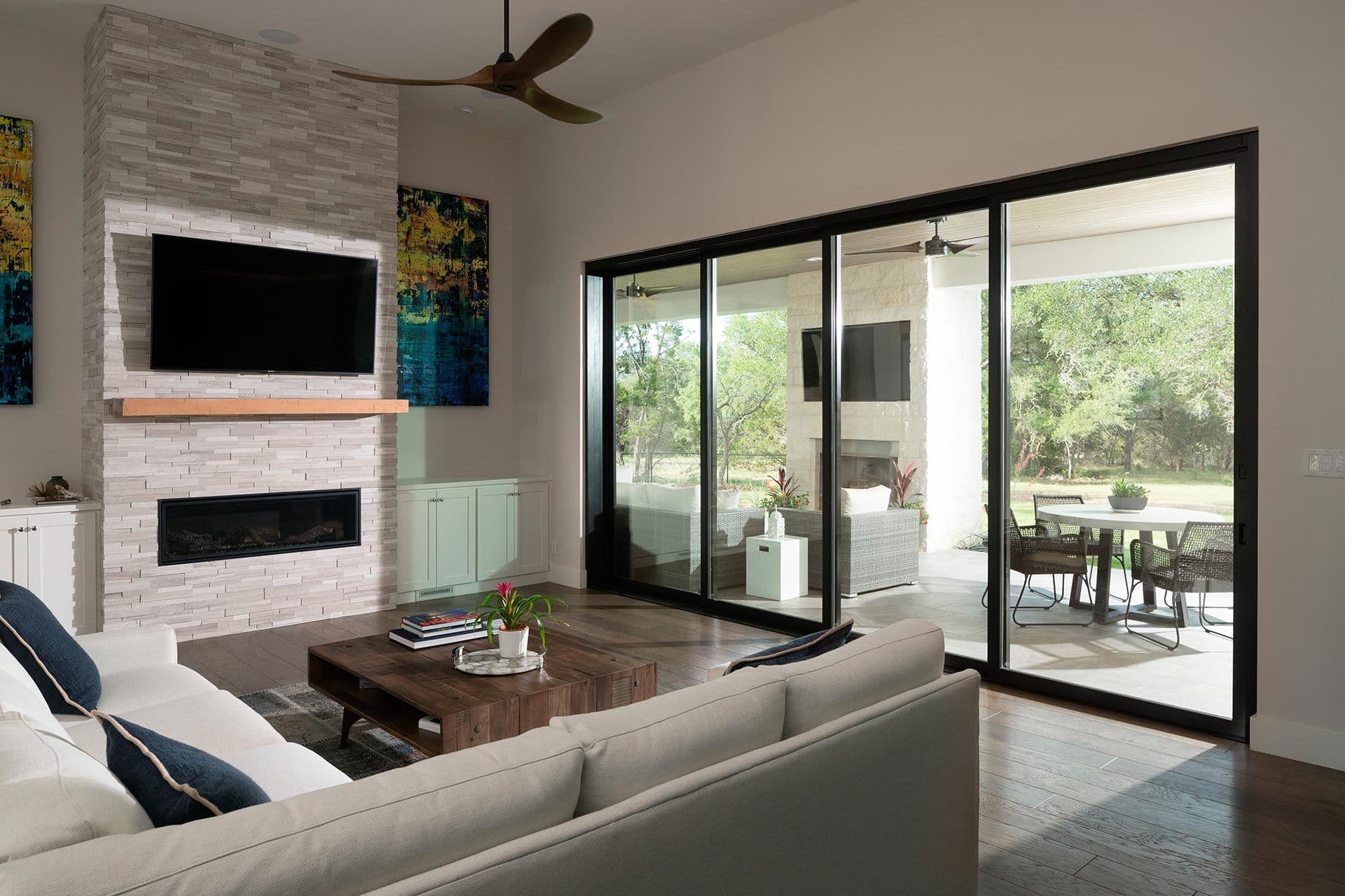 A modern, gray living room with sliding glass patio doors with black frames.