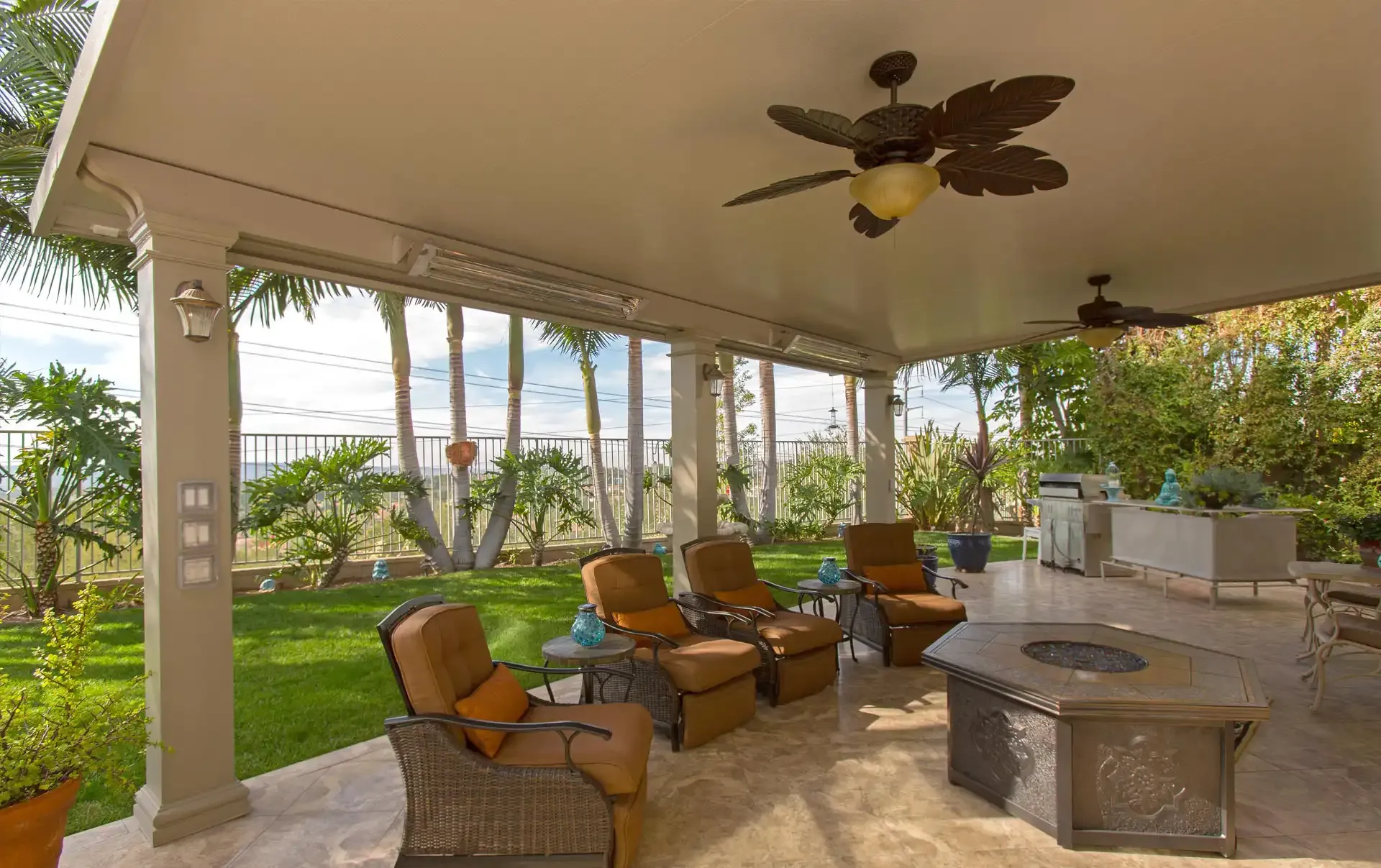 A covered patio with seating area, fire pit, and ceiling fans.
