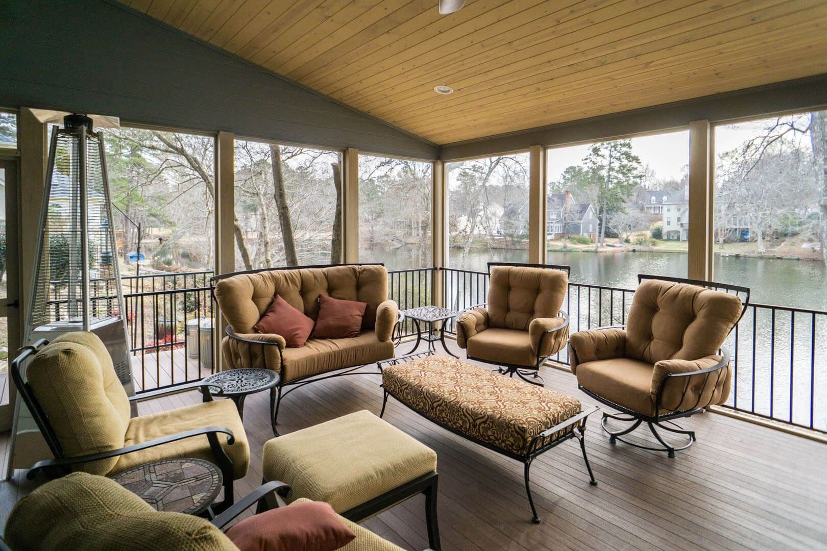 A covered outdoor deck porch with black railings and patio furniture by Outback Deck.
