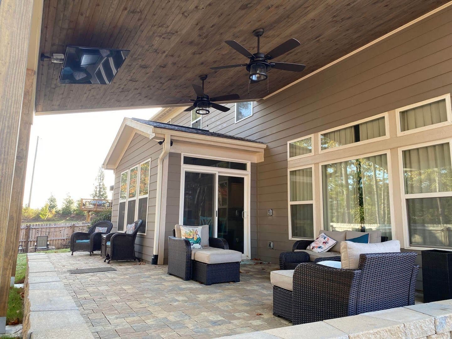 A covered patio with ceiling fans by Outback Deck.