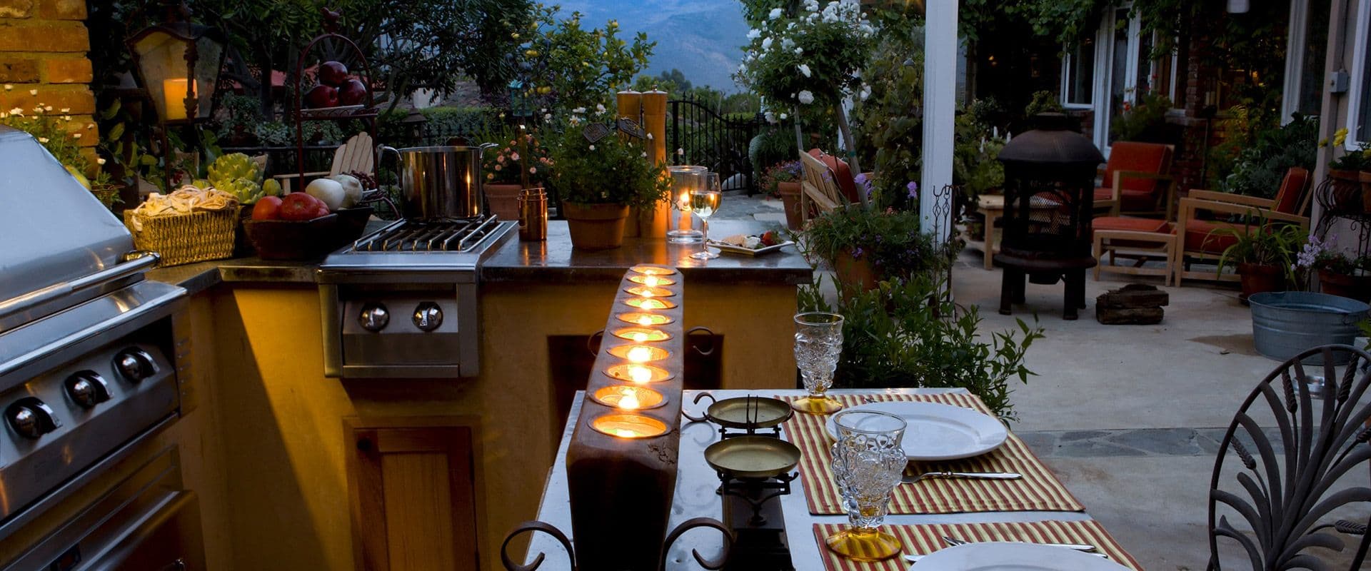 A deck with an outdoor kitchen at dusk.