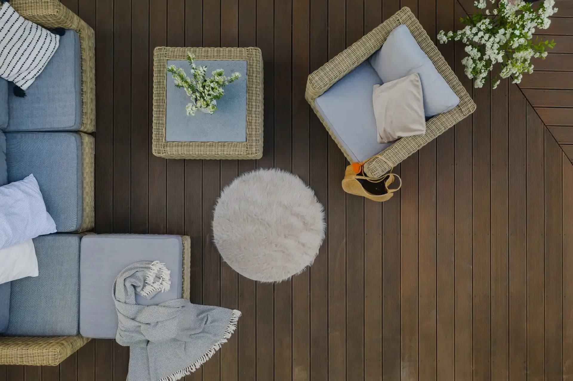 A top down overhead view of patio furniture on a dark brown composite deck.