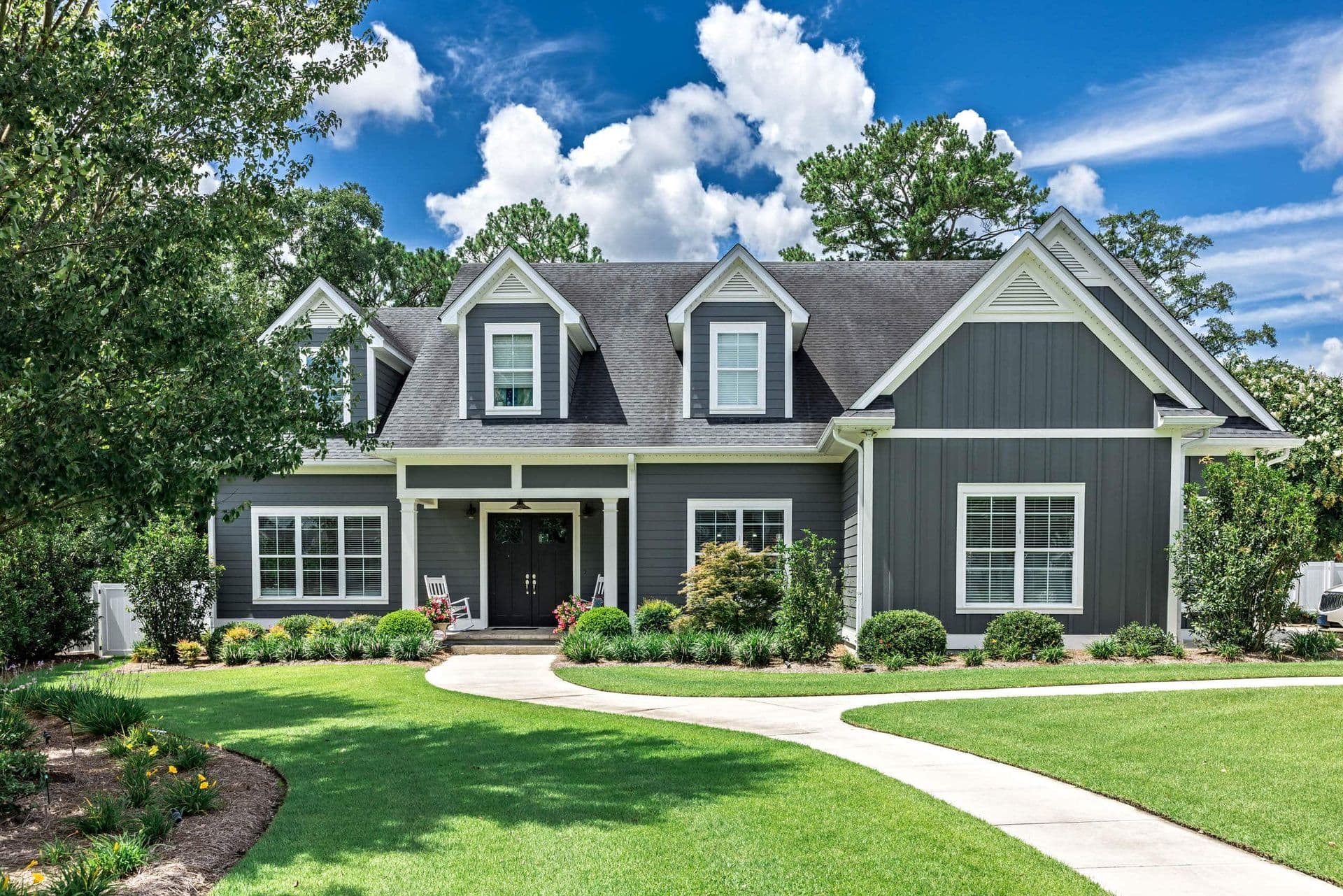 A dark gray house with white trim and double-hung windows.