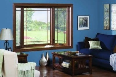 A bay window with brown wood frame in a blue living room.