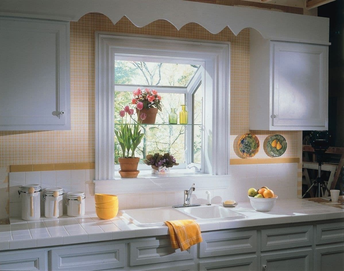 A yellow kitchen with gray cabinets and a garden window above the sink.