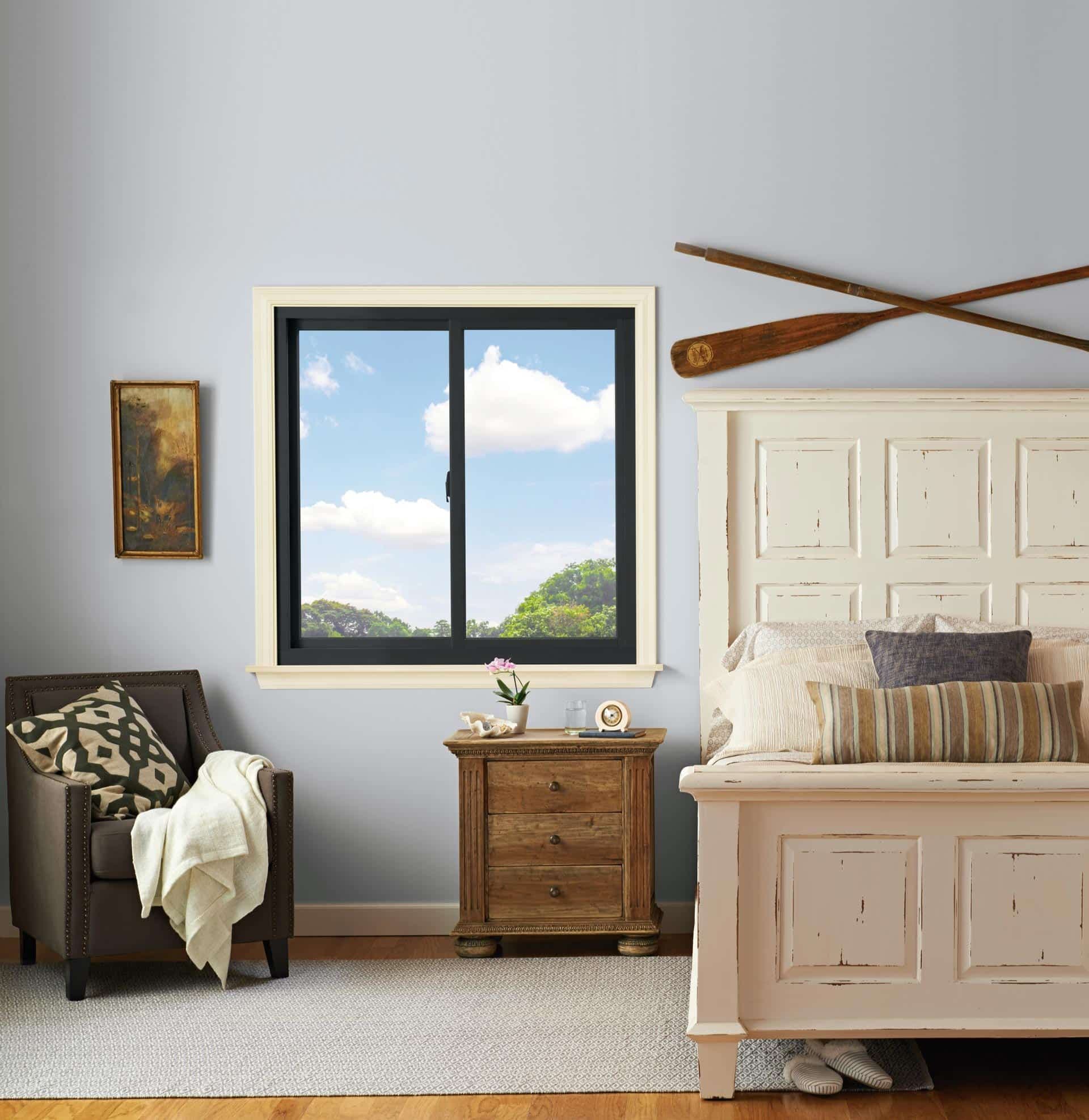 Sliding windows in black frames in a light gray-blue bedroom.
