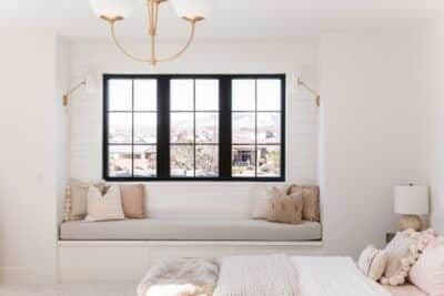 A white bedroom with window bench seating and windows with black frames.