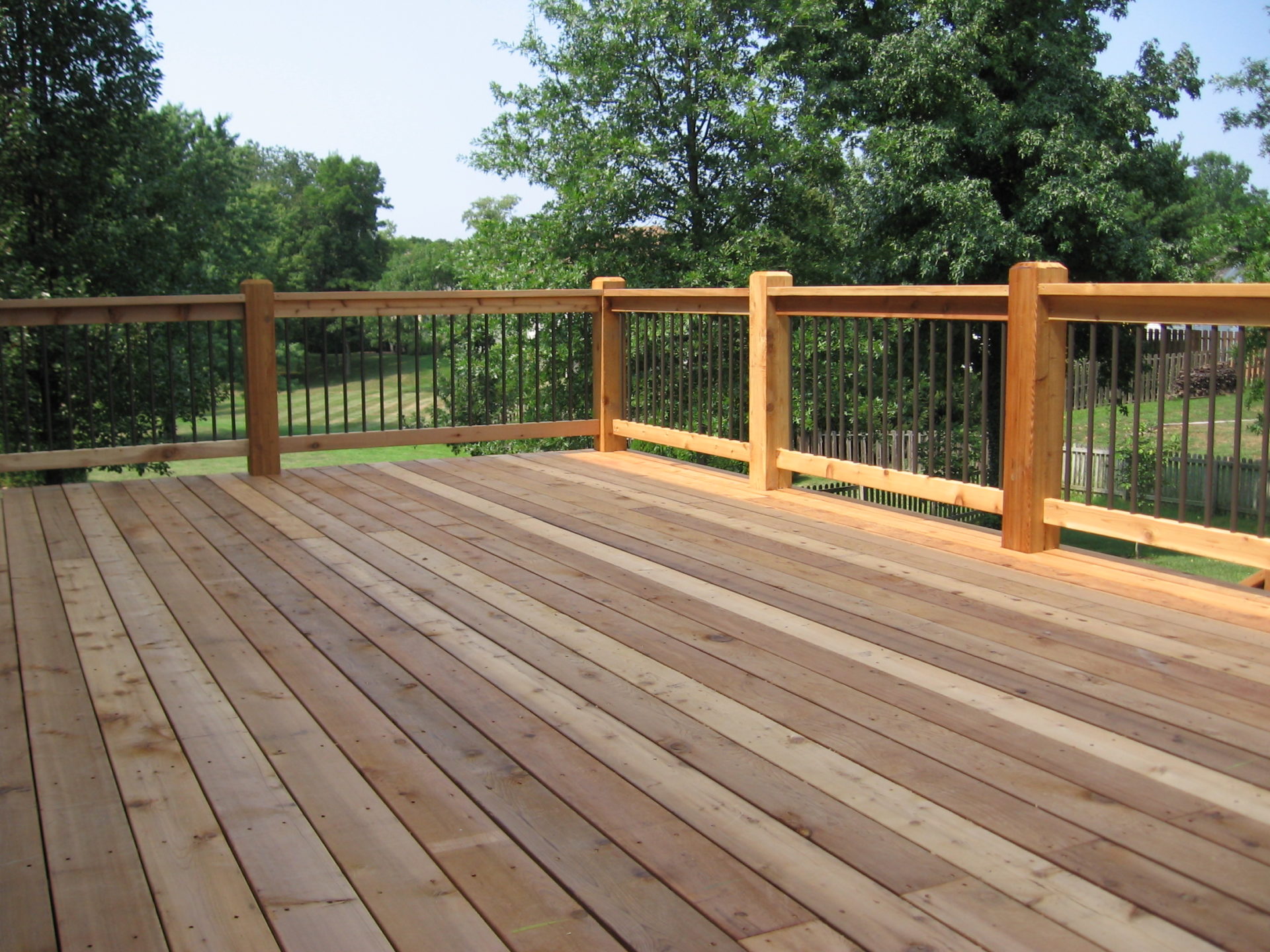 A large wood deck with a wood railing.
